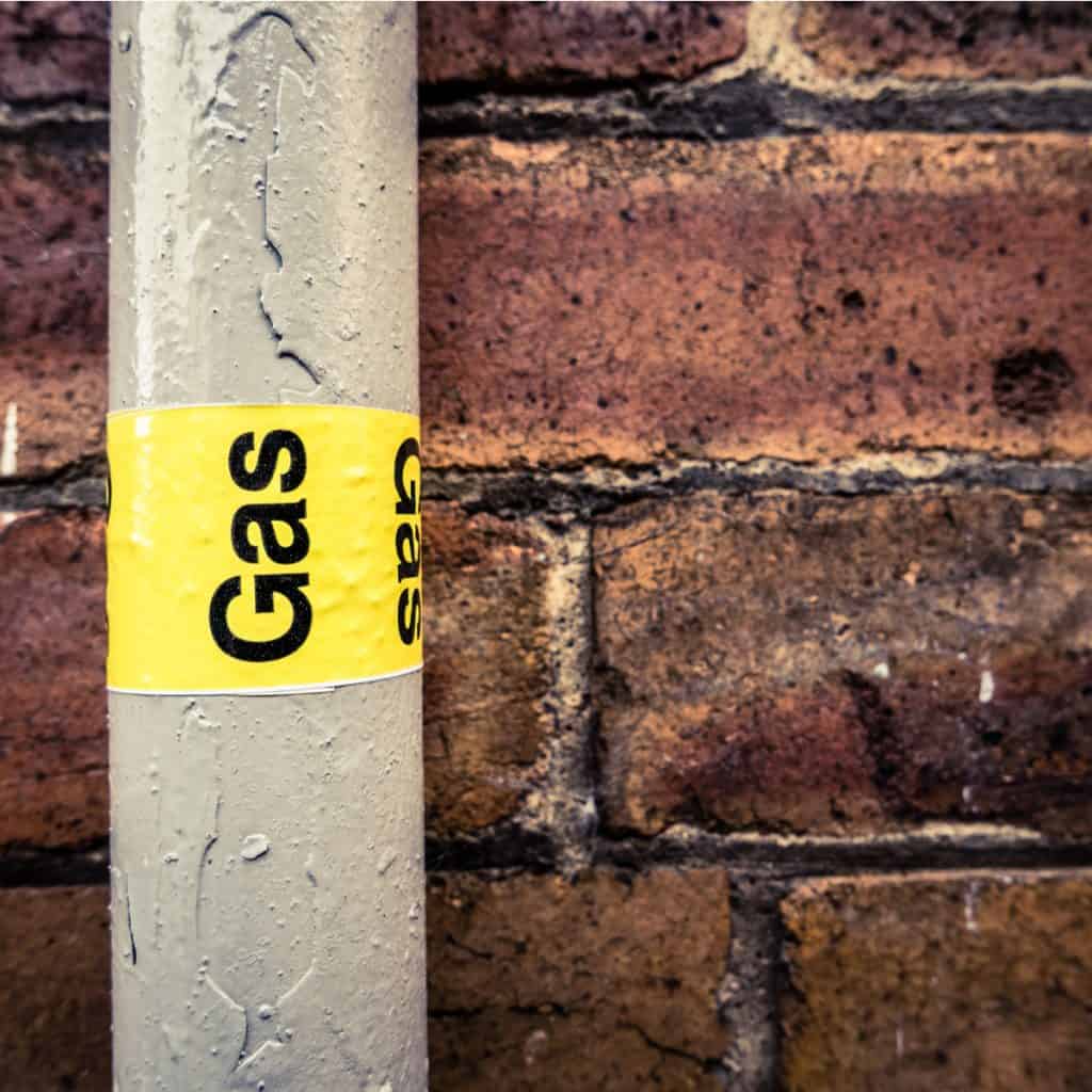 Yellow gas pipe label on brick wall.